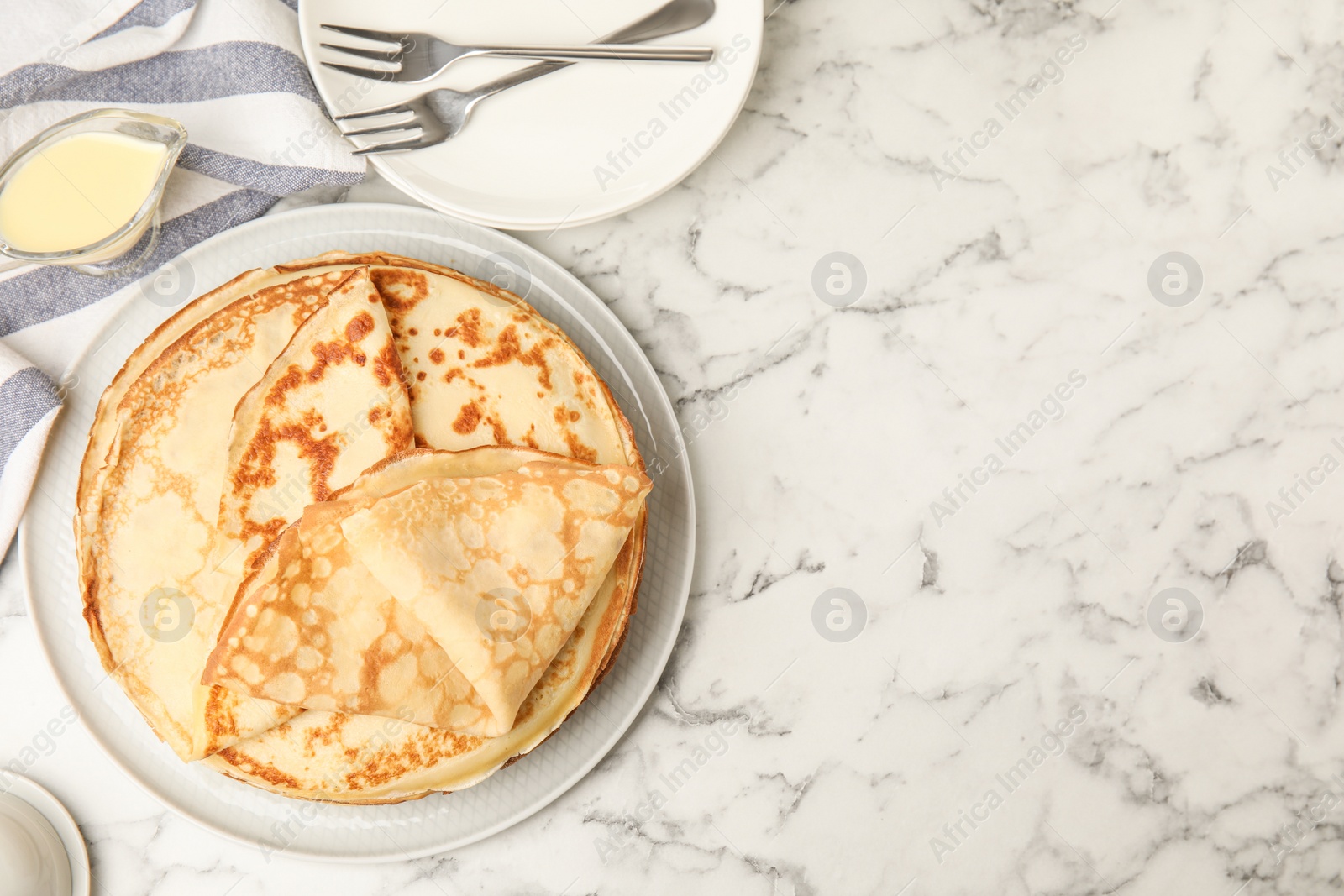 Photo of Flat lay composition with fresh thin pancakes on white marble table. Space for text