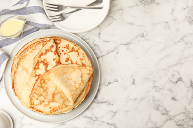 Flat lay composition with fresh thin pancakes on white marble table. Space for text