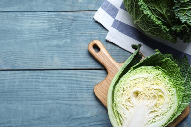 Photo of Cut fresh savoy cabbages on blue wooden table, flat lay. Space for text