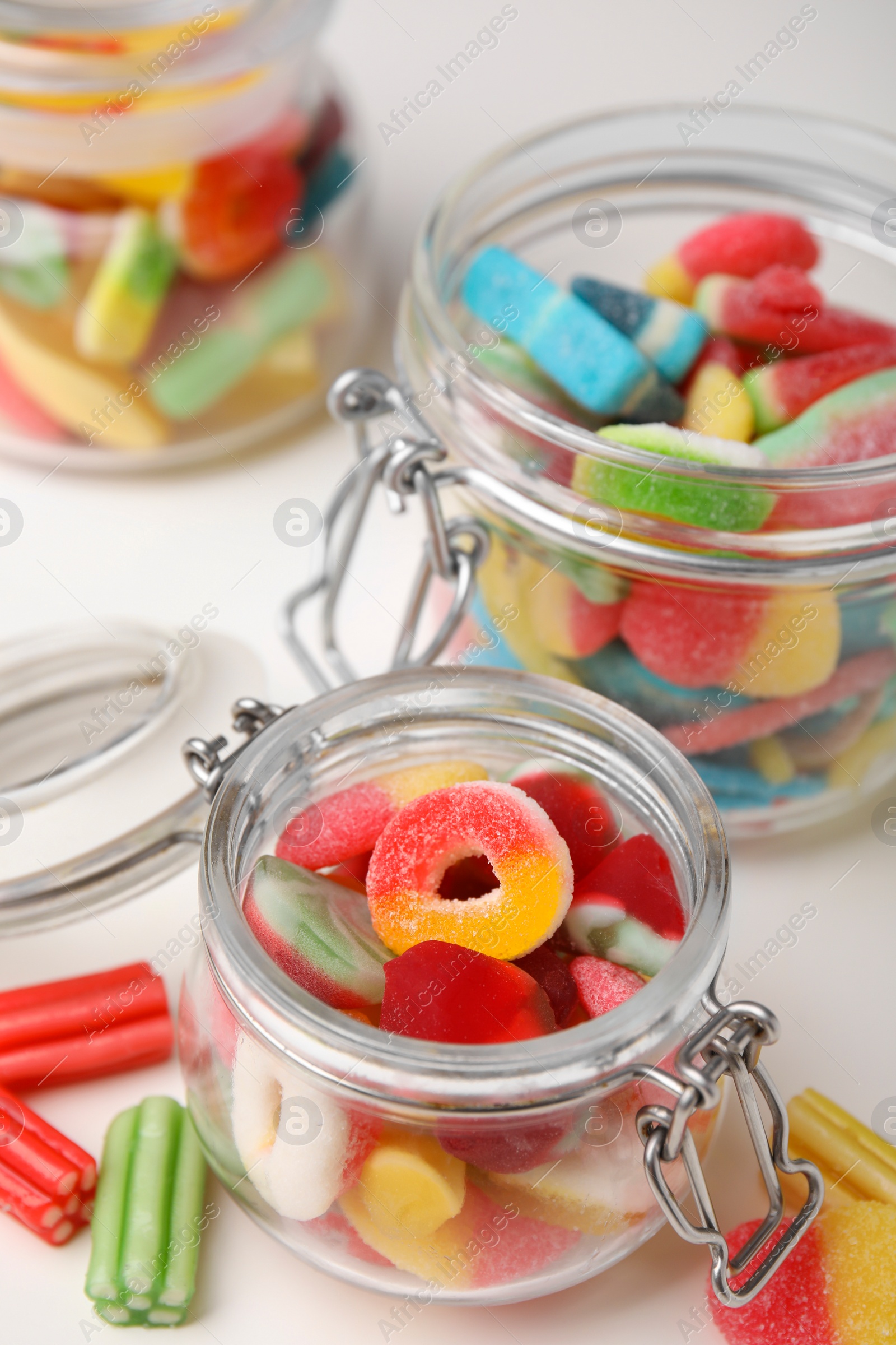 Photo of Tasty jelly candies in jars on white table