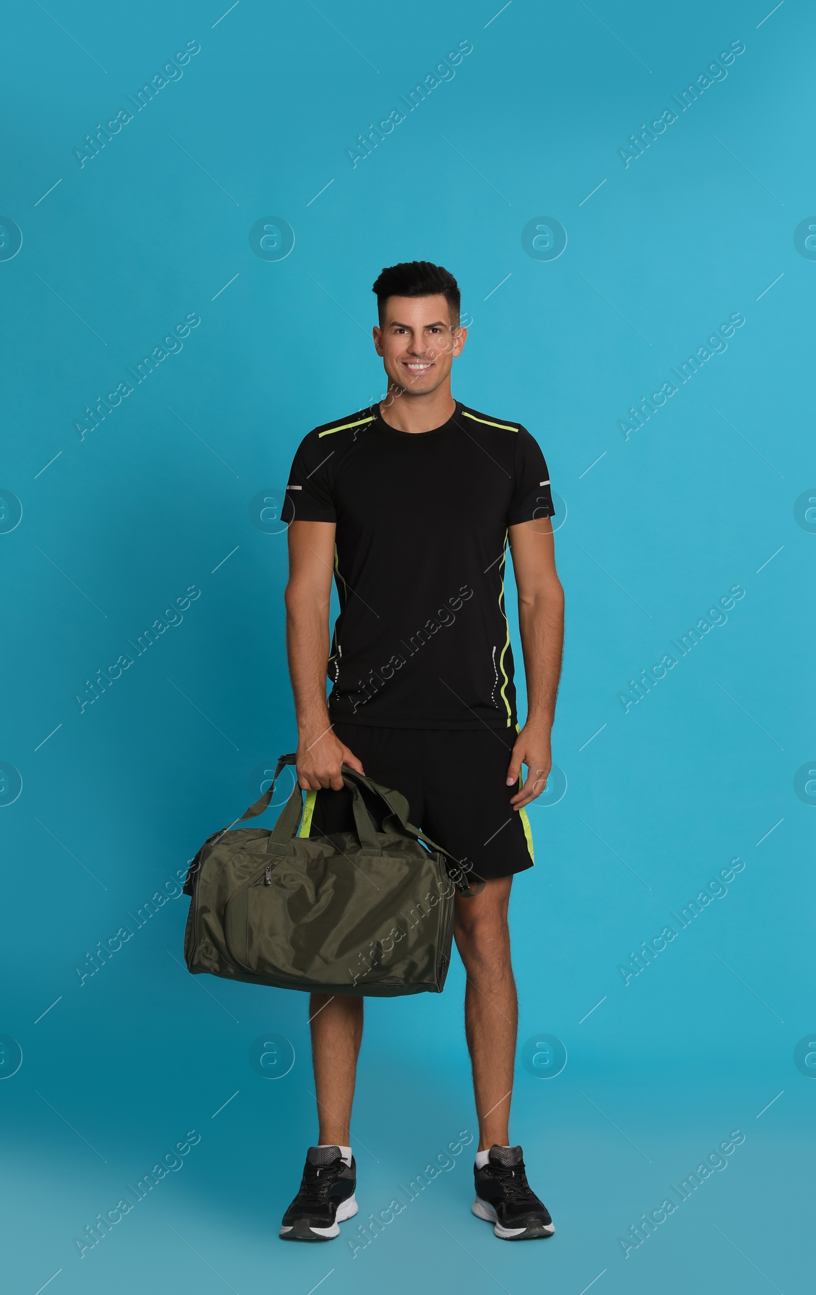 Photo of Handsome man with sports bag on light blue background