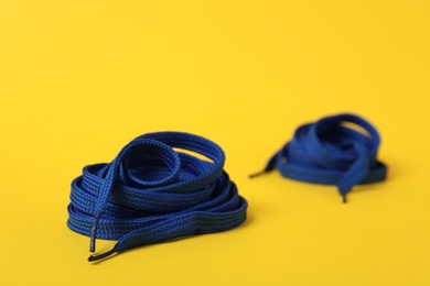 Photo of Blue shoe laces on yellow background. Space for text