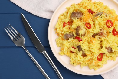 Delicious pilaf with meat served on blue wooden table, flat lay