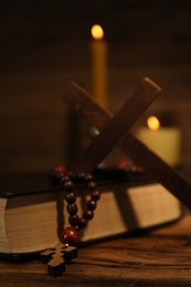 Photo of Bible, cross, rosary beads and church candles on wooden table, closeup