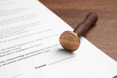 One stamp tool and document on wooden table, closeup