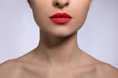 Photo of Young woman with beautiful lips makeup on light background, closeup