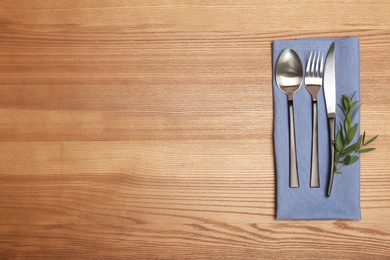 Photo of Cutlery and napkin on wooden background, top view. Table setting