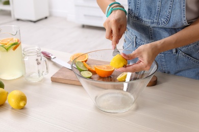 Photo of Young woman squeezing juice in bowl for lemonade on table, closeup. Natural detox drink
