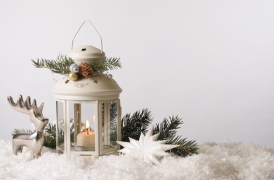 Beautiful composition with vintage Christmas lantern and festive decorations on snow against white background. Space for text