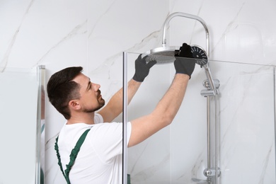 Photo of Professional handyman working in shower booth indoors