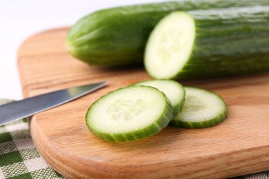 Photo of Cucumbers, knife and cutting board on table, closeup