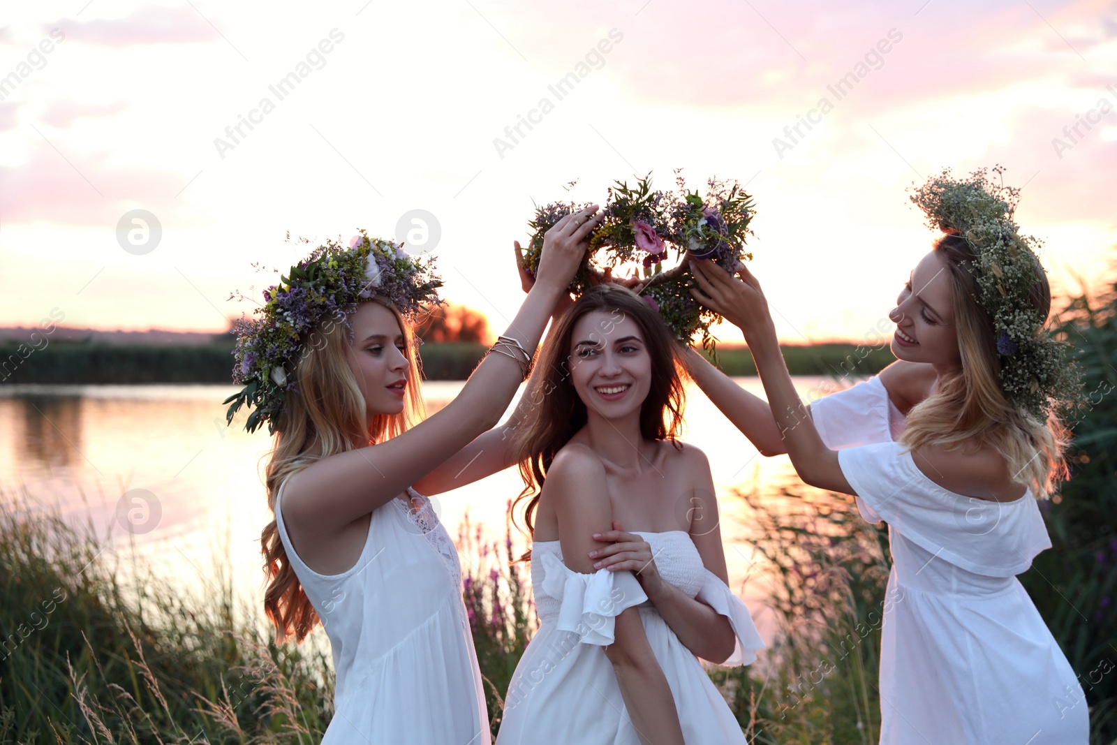 Photo of Young women wearing wreaths made of beautiful flowers outdoors at sunset