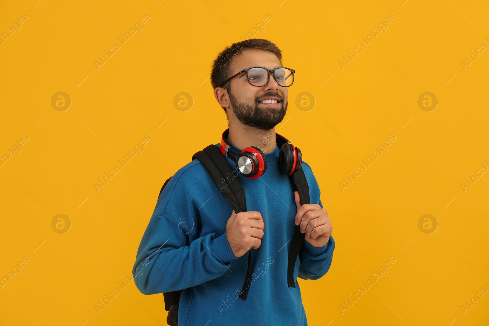 Photo of Student with headphones and backpack on yellow background