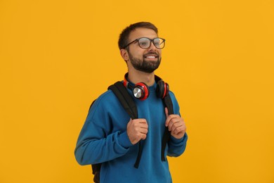 Student with headphones and backpack on yellow background