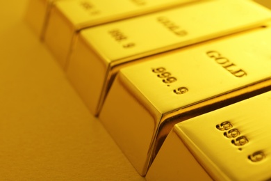 Photo of Shiny gold bars on color background, closeup