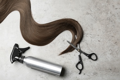 Photo of Flat lay composition with hair lock and tools on grey background