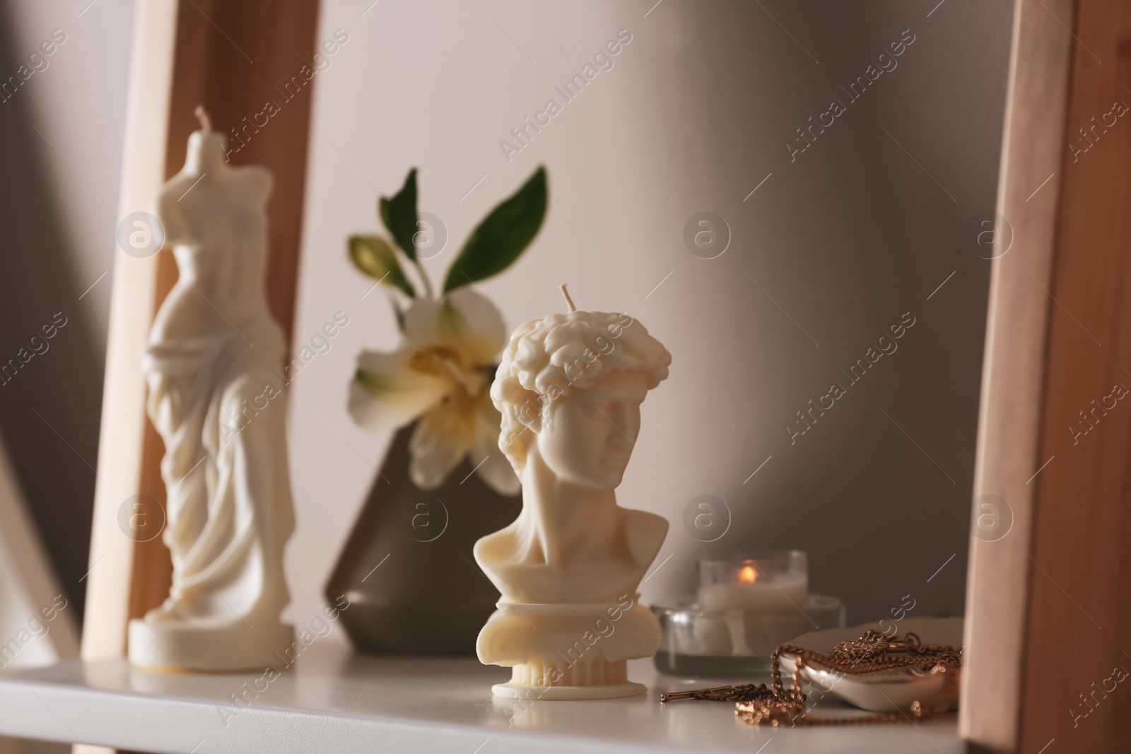 Photo of Beautiful David bust candle and jewelry on shelf