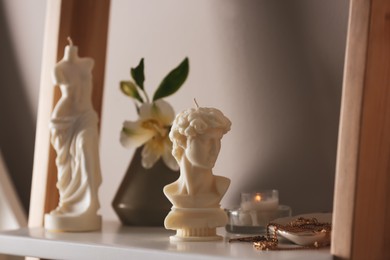 Photo of Beautiful David bust candle and jewelry on shelf