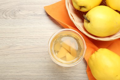 Photo of Delicious quince drink in glass and fresh fruits on wooden table, top view. Space for text