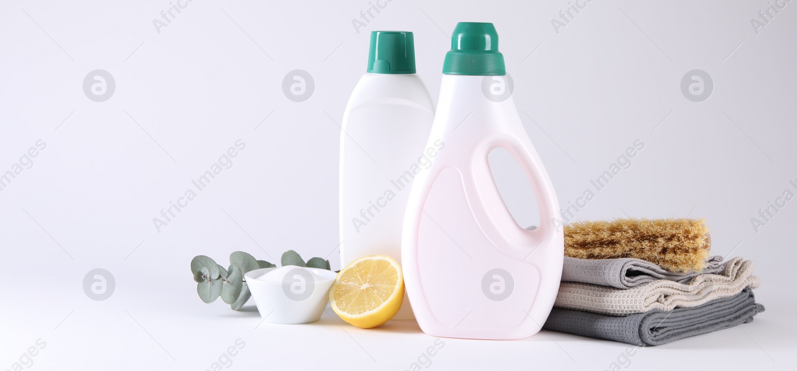 Photo of Bottles of cleaning product, brush, rags and lemon on light background. Banner design