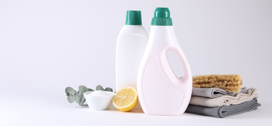 Bottles of cleaning product, brush, rags and lemon on light background. Banner design