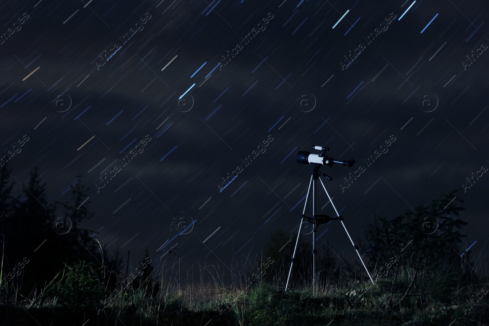 Photo of Modern telescope and beautiful sky in night outdoors. Star trail