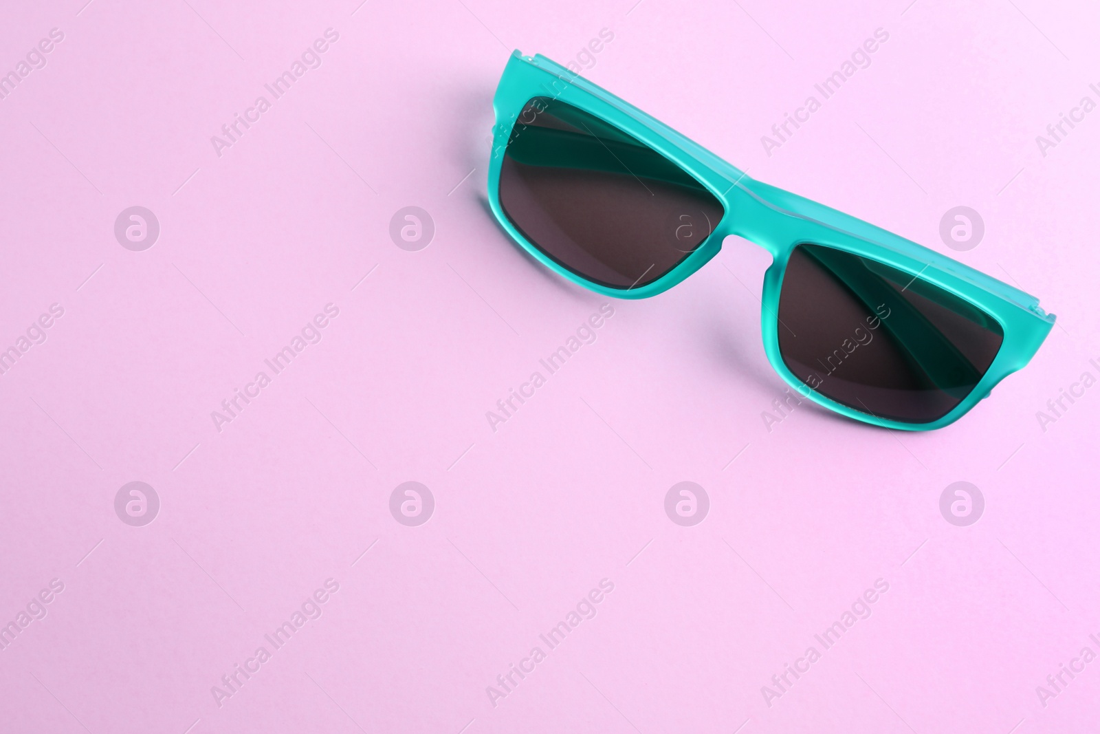 Photo of Stylish sunglasses on light violet background, top view. Space for text