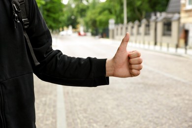 Photo of Man catching car on city street, closeup. Hitchhiking trip