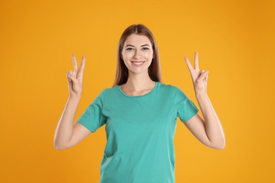 Photo of Woman showing number four with her hands on yellow background