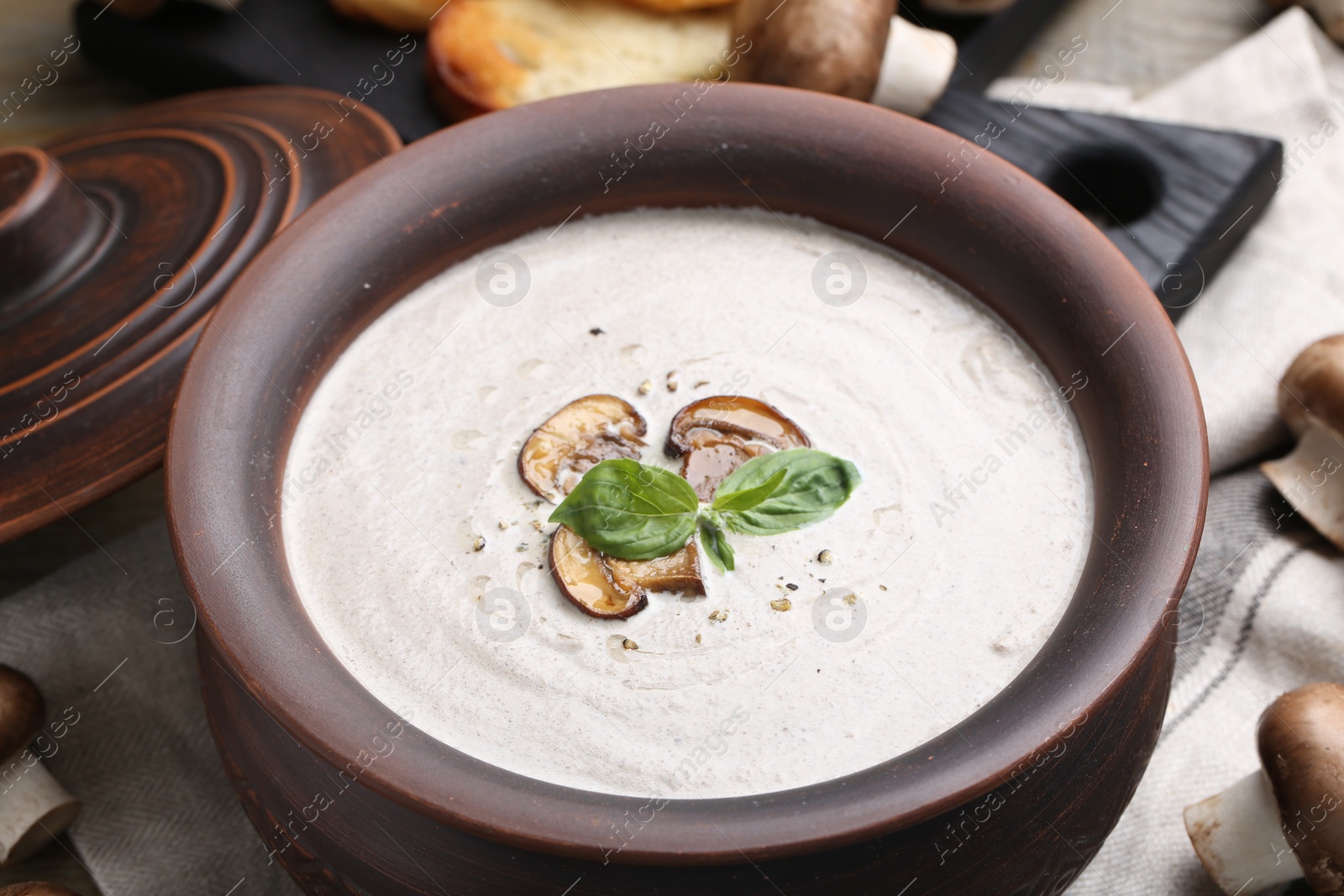 Photo of Fresh homemade mushroom soup in ceramic pot on table, closeup