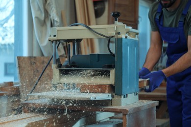 Professional carpenter working with grinding machine in shop, closeup