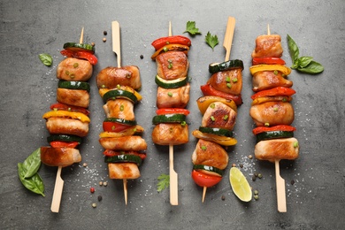 Photo of Delicious chicken shish kebabs with vegetables and herbs on grey table, flat lay