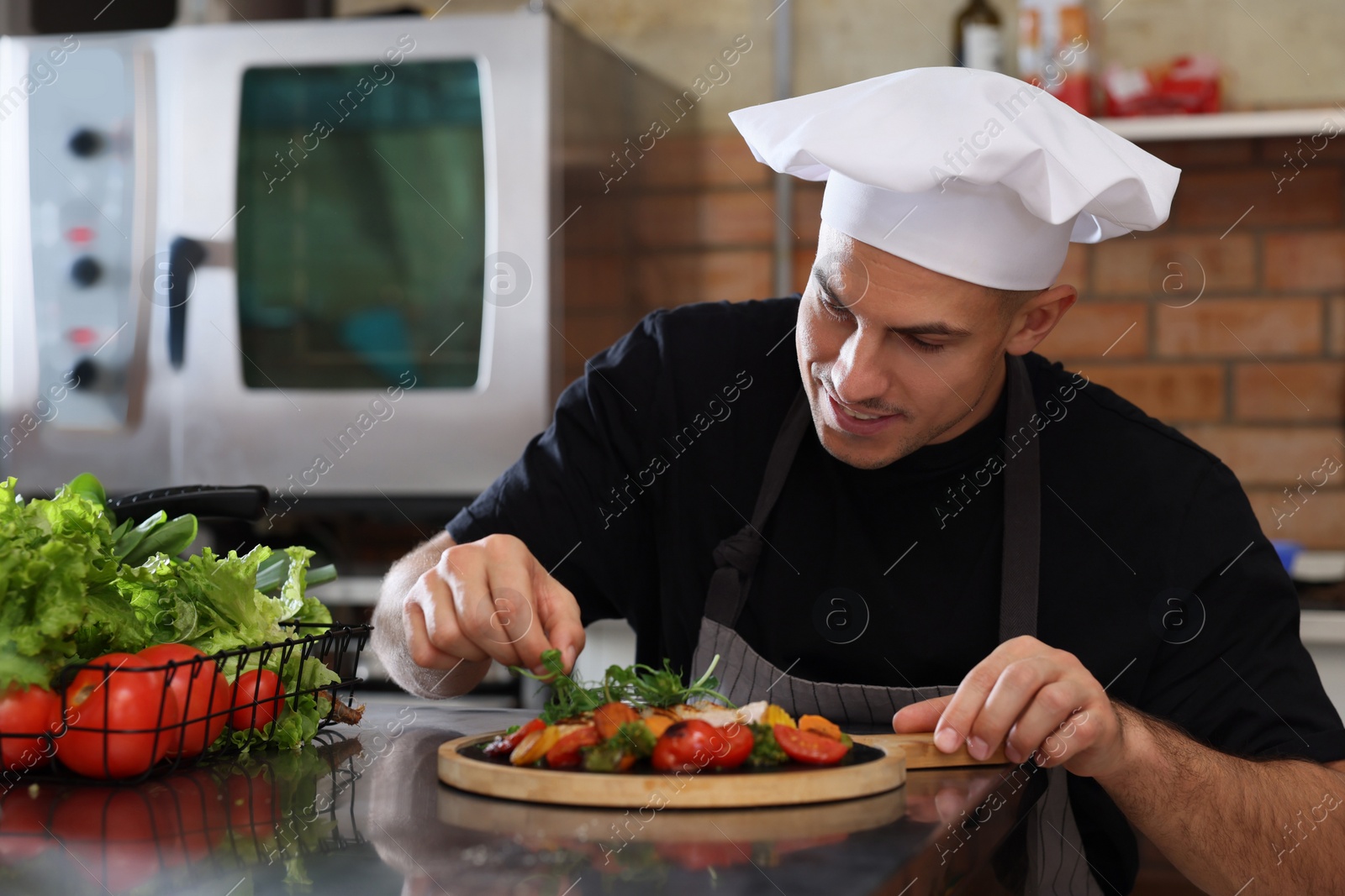 Photo of Professional chef adding microgreens to cooked dish in restaurant kitchen