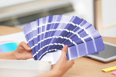 Image of Designer with color palette samples at table, closeup