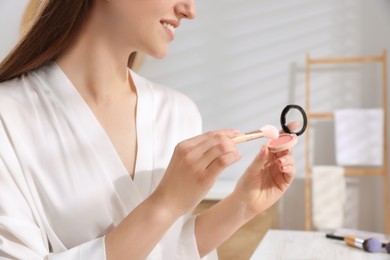 Woman with blusher and brush at dressing table indoors, closeup