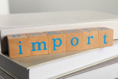 Photo of Word Import made of wooden cubes on books, closeup