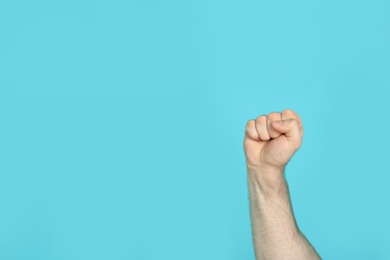 Photo of Young man showing clenched fist on color background. Space for text