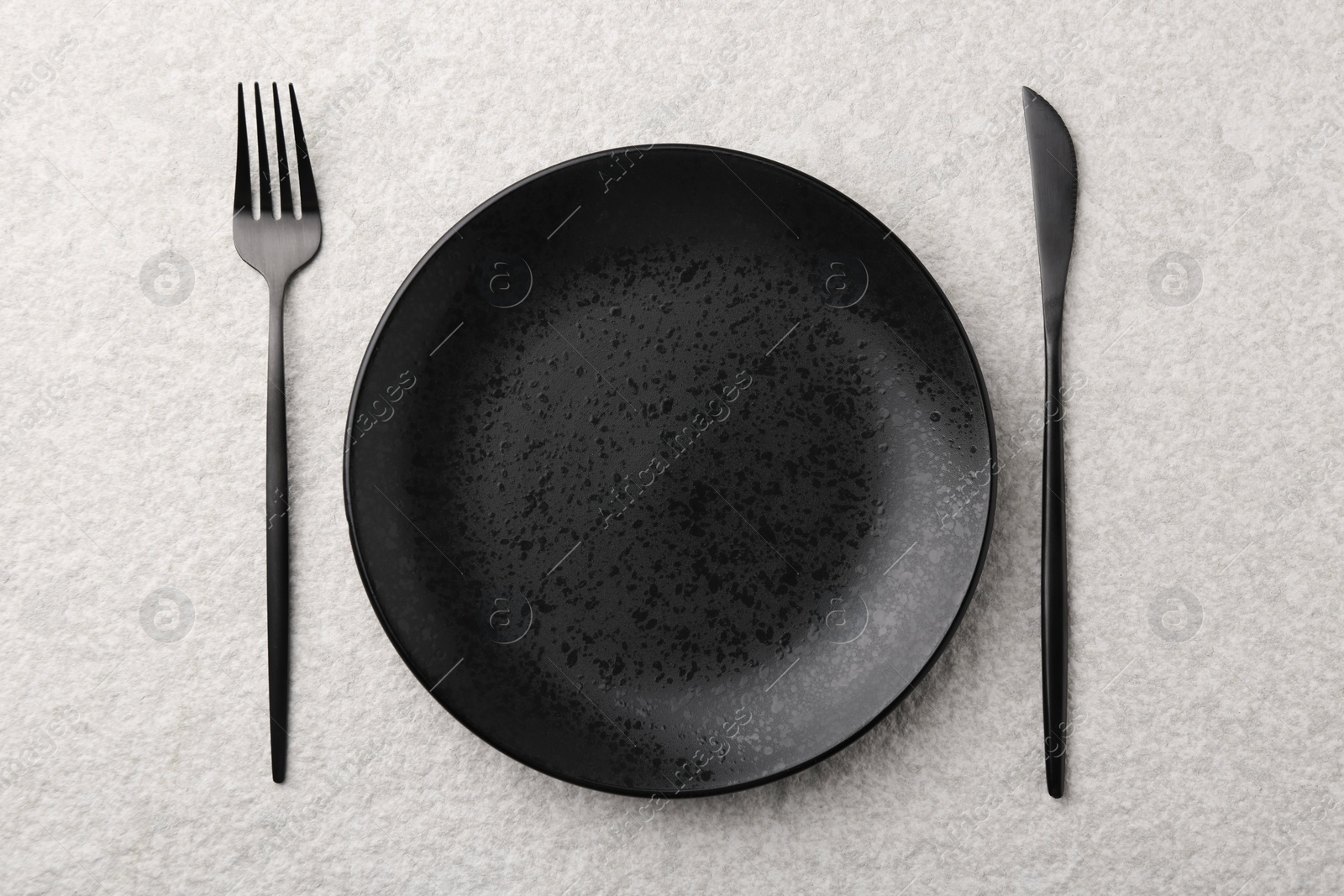 Photo of Stylish setting with elegant cutlery on beige textured table, top view