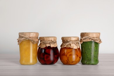 Photo of Jars with preserved fruit jams on white wooden table