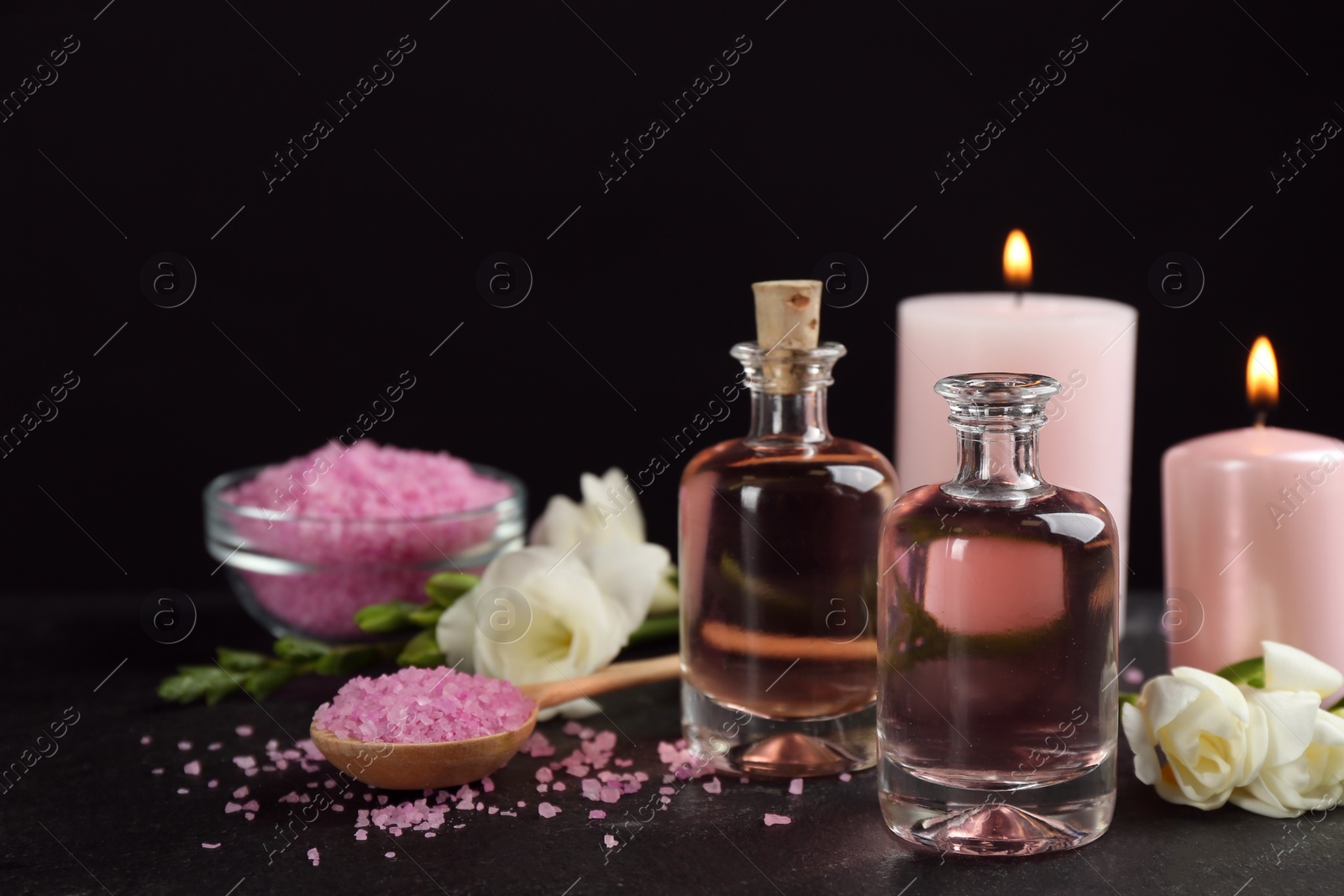 Photo of Beautiful spa composition with essential oil and candles on black table. Space for text