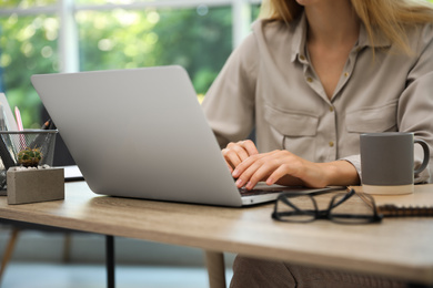 Photo of Young woman working with laptop in office, closeup