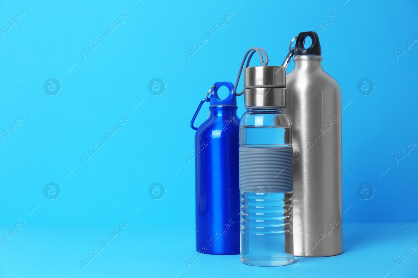 Photo of Different sport bottles with space for text on color background