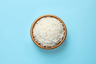 Bowl of tasty cooked rice on color background, top view