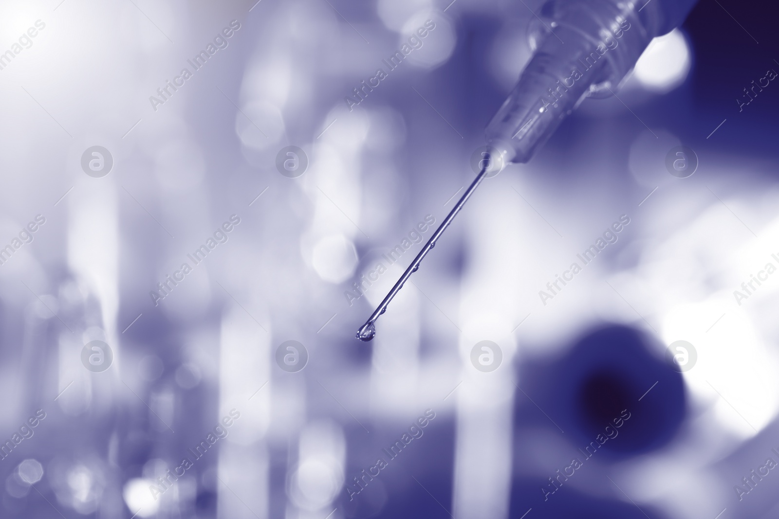 Image of Syringe with medicine against blurred background, toned in purple