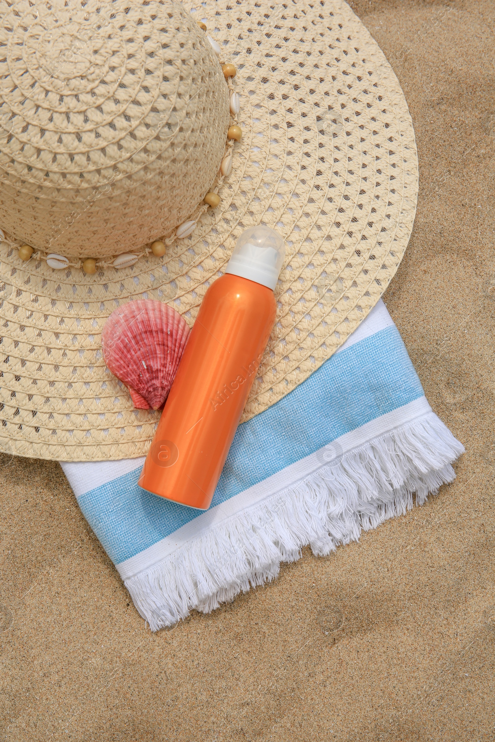 Photo of Sunscreen, hat, seashell and towel on sand, flat lay. Sun protection care