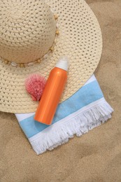 Sunscreen, hat, seashell and towel on sand, flat lay. Sun protection care
