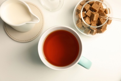 Photo of Cup of black tea and milk on table, top view