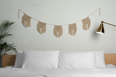 Photo of Stylish macrame hanging on white wall in bedroom