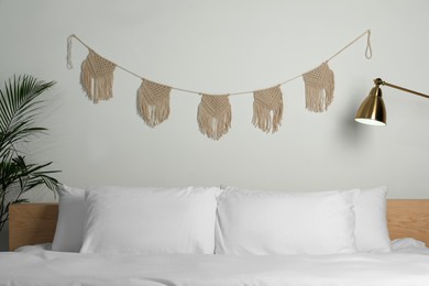 Stylish macrame hanging on white wall in bedroom