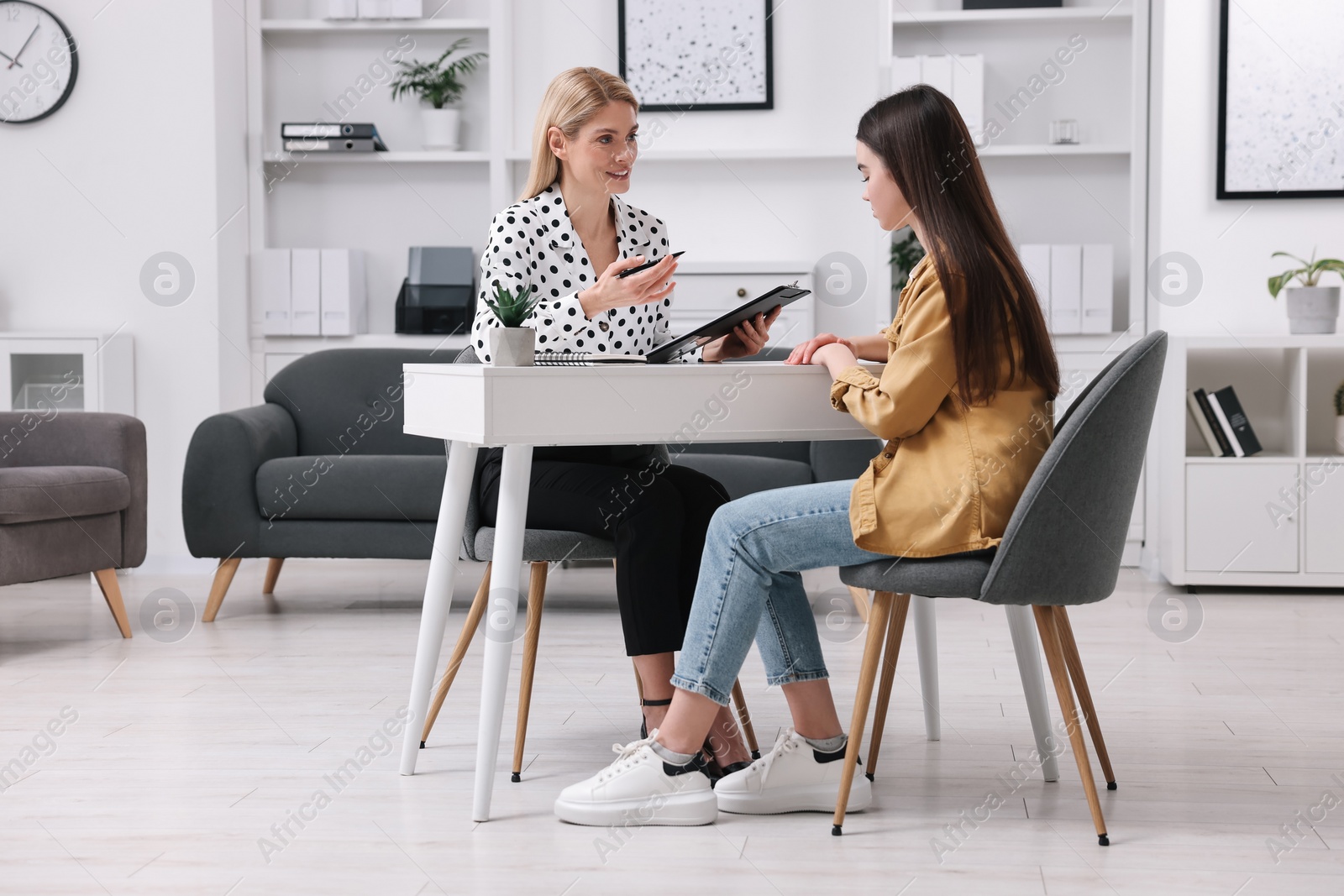 Photo of Psychologist working with teenage girl at table in office